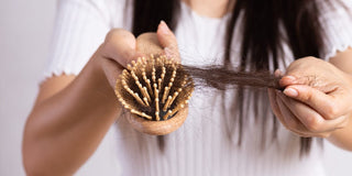 Lady pulling hair out of her brush, suffering from hair loss