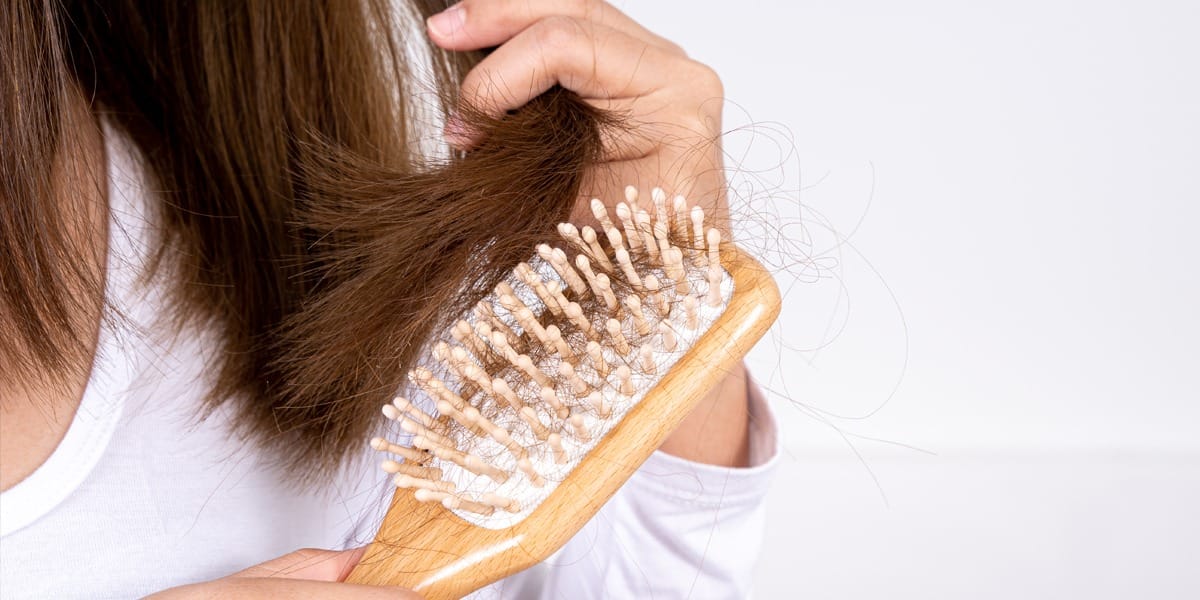 Lady brushing her hair, suffering from alopecia