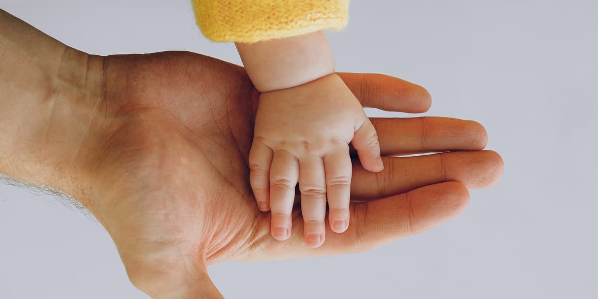 A baby's hand in their fathers hand