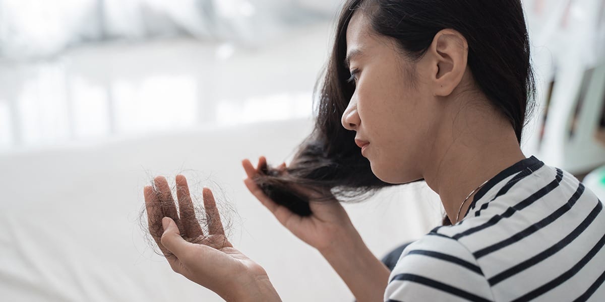 Lady suffering from hair loss with hair in her hands