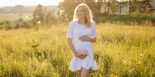 Pregnant lady in a field holding her bump
